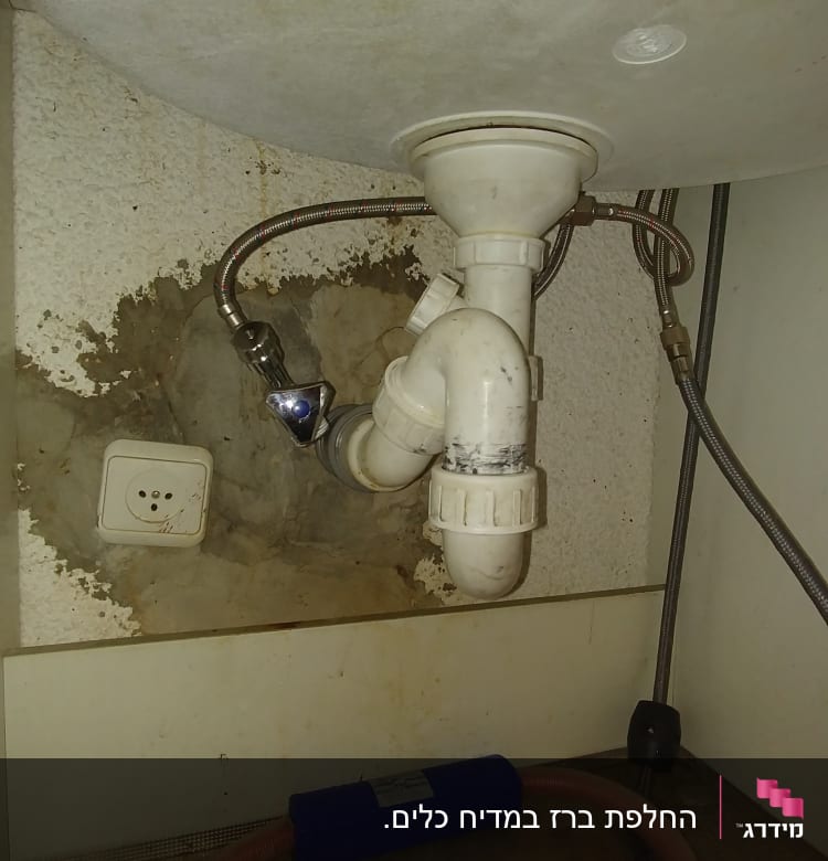צנרת מתחת לכיור עם חיבורים וצינור פלסטיק